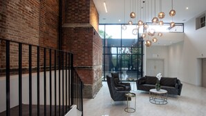 A modern interior with a brick wall, a staircase, and a seating area with two sofas and a coffee table. - Winstanley House (Leicester)