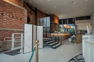 Un interior moderno con pared de ladrillo, un mostrador de recepción y una escalera que sube a los pisos superiores.
