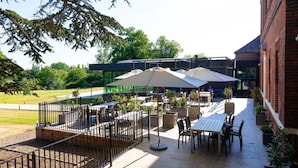 An outdoor patio area with tables and chairs, umbrellas, and potted plants. - Winstanley House (Leicester)