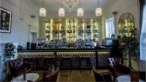 A bar area with a bar counter, multiple seating options, and a chandelier. - Winstanley House (Leicester)