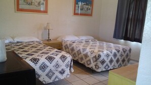 A room with two beds, a nightstand with a lamp, and two framed pictures on the wall. - Ocean Crest Motel (Ormond Beach)