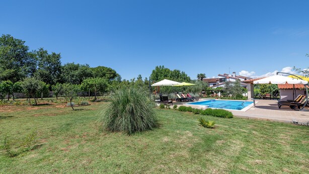 A backyard with a swimming pool, lounge chairs, and umbrellas. - Apartments Neva (Pula)