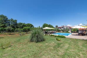 Un patio trasero con piscina, sillas de descanso y sombrillas.