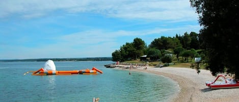 A beach with clear water, a lifebuoy, and a red boat.
