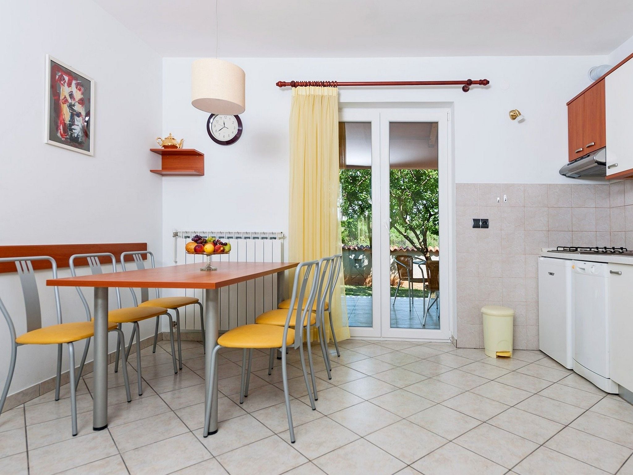 Une cuisine de taille réduite avec un coin repas, une horloge et un radiateur.