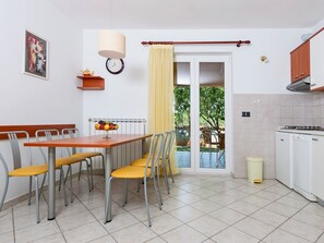 A compact kitchen with a dining area, a clock, and a radiator. - Apartments Neva (Pula)