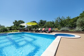 Una piscina con sillones de descanso y un paraguas amarillo.