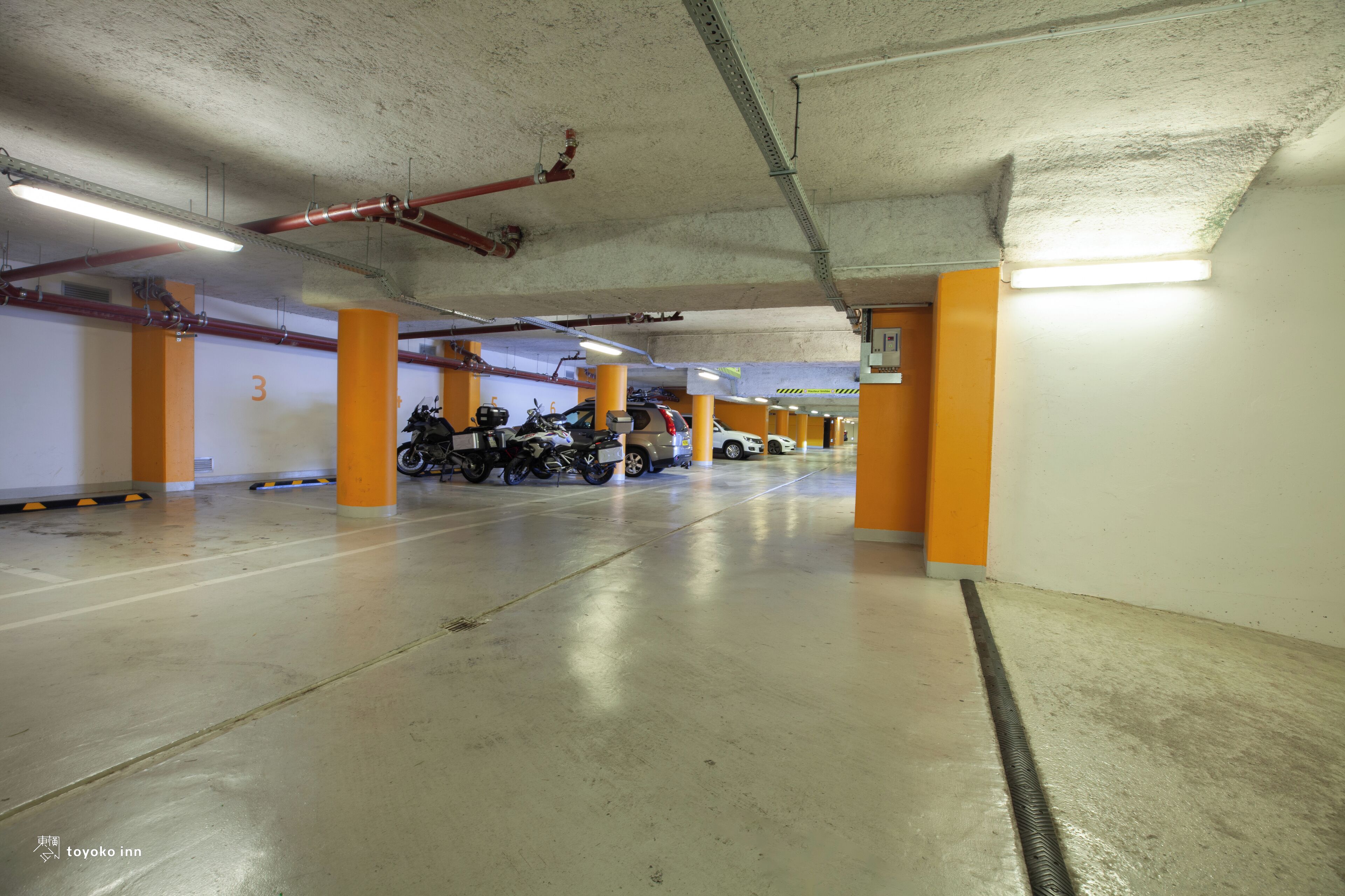 A multi-level parking garage with concrete floors and orange pillars.