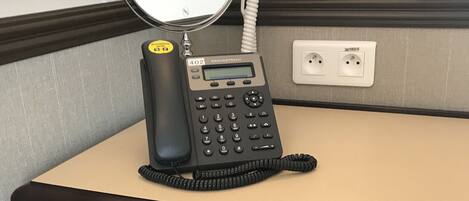 A hotel reception desk with a Grandstream phone, a coffee maker, and a Nescafe coffee pod.