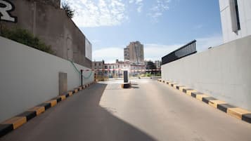 Una calle urbana vacía, con un muro de concreto a la izquierda y un edificio a la derecha.