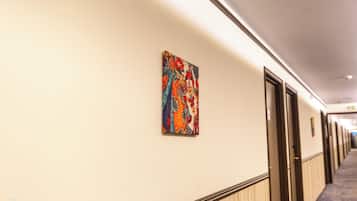 Un couloir d’hôtel orné d’une œuvre d’art colorée sur le mur, les portes et le sol recouvert d’une moquette.