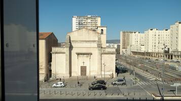 A church with a large central dome and a bell tower, surrounded by modern buildings and a busy street with cars.