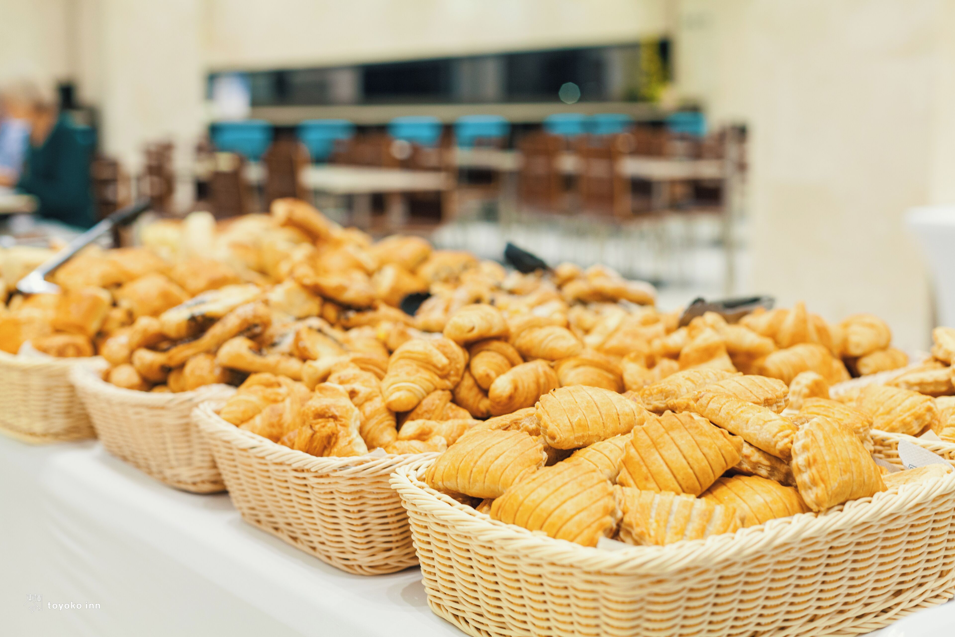 Una mesa de buffet con canastas de cruasanes y otros productos de pastelería.