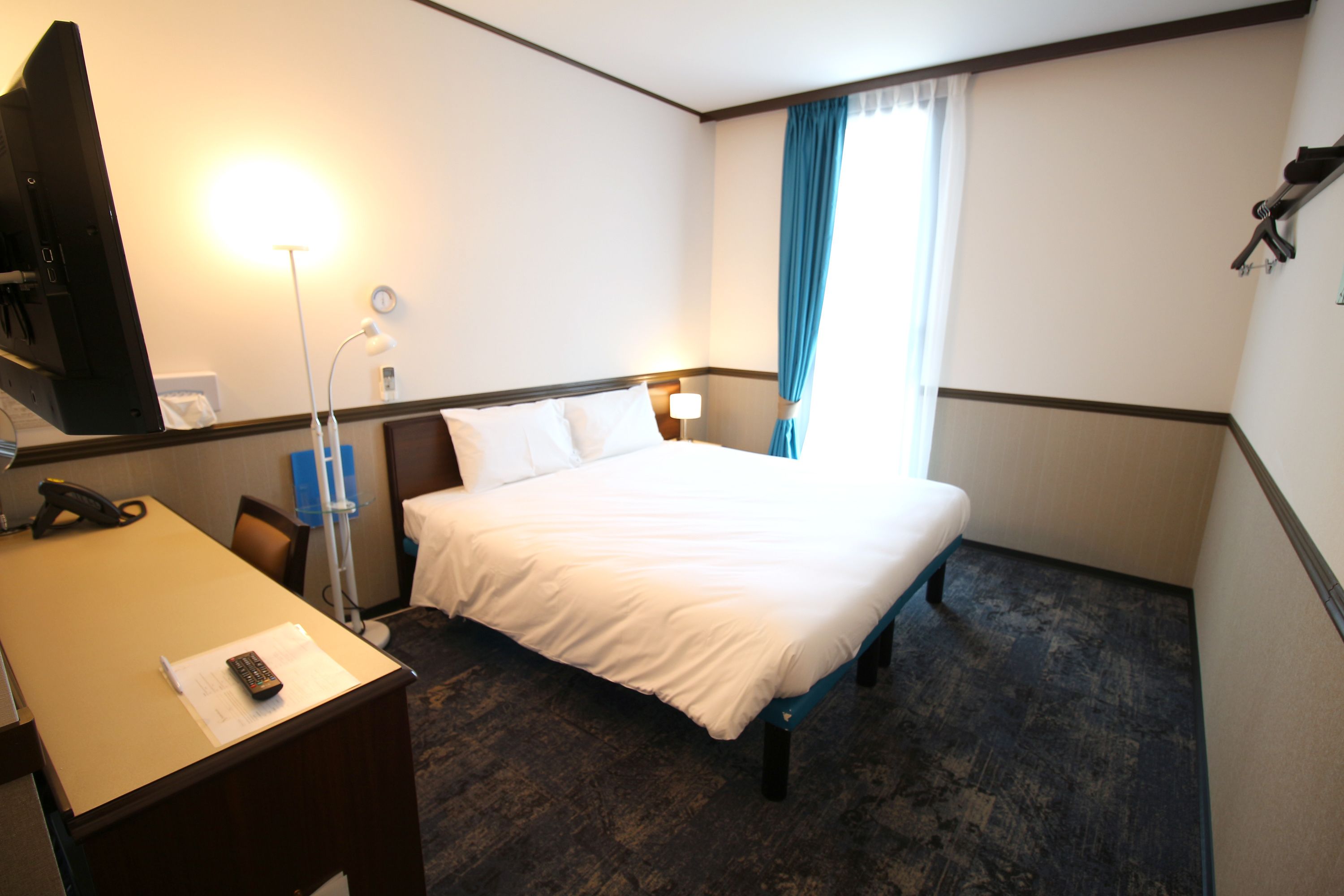 Una habitación de hotel con cama, escritorio, lámpara y teléfono.