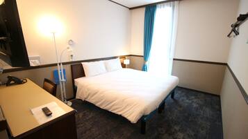 Una habitación de hotel con cama, escritorio, lámpara y teléfono.
