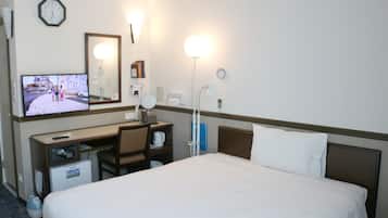 A hotel room with a bed, desk, chair, television, clock, and bedside lamp.