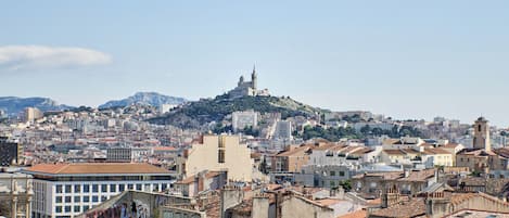 A cityscape with a prominent hilltop building, surrounded by densely packed buildings with red-tiled roofs.