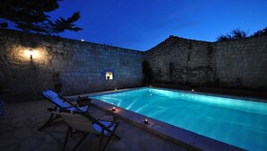 A swimming pool with stone walls and a few lounge chairs. - 1882 Butik Otel (Cesme)