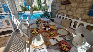 An outdoor dining area with a pool view, stone walls, and a white canopy. - 1882 Butik Otel (Cesme)