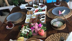 A wooden dining table set with various food items, including bread, salads, and condiments. - 1882 Butik Otel (Cesme)