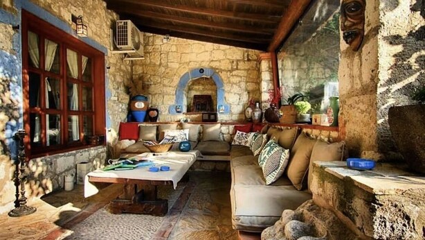 A cozy, rustic interior with stone walls, a wooden ceiling, and a central seating area with cushions and a table. - 1882 Butik Otel (Cesme)