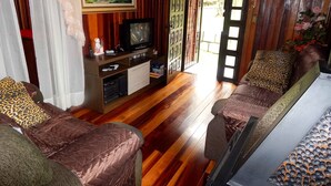 A living room with two brown sofas, a television, and a painting of a landscape. - Chale Bosque da Serra (Canela)