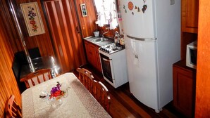 A compact kitchen with wooden cabinets, a refrigerator, a stove, and a sink. - Chale Bosque da Serra (Canela)