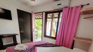 Un dormitorio con cama, televisión, escritorio y vistas al exterior.