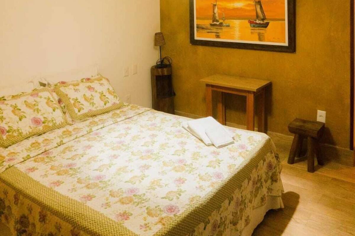 A bedroom with a bed, a nightstand, a lamp, and a painting on the wall.