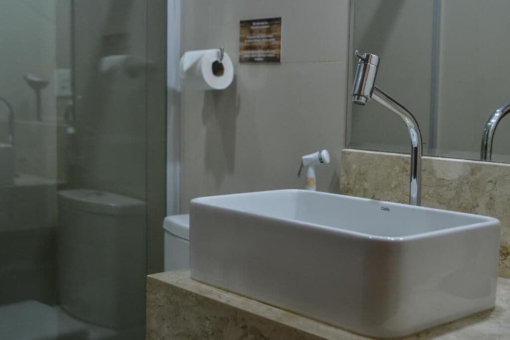 A bathroom with a rectangular sink, a mirror, and a shower area.