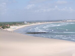 A beach with a sandy shore, a few umbrellas, and buildings in the distance.