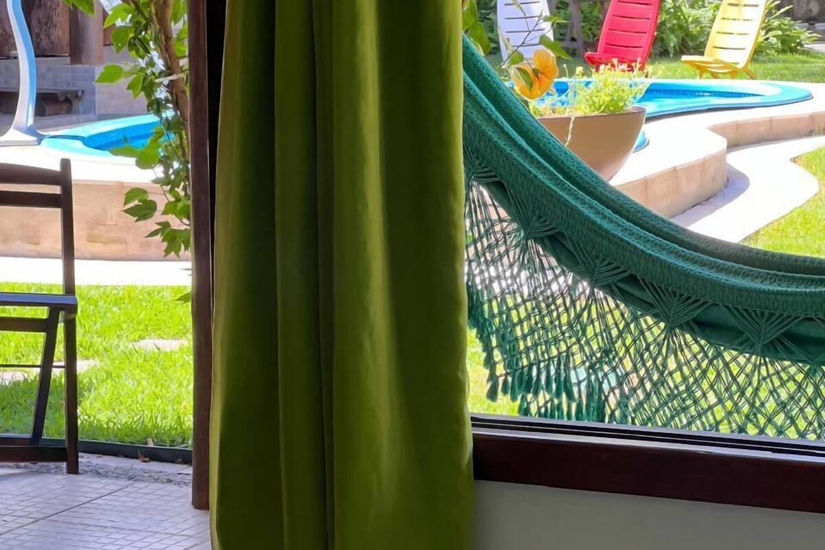 A room with a view of a swimming pool, a hammock, and outdoor seating.