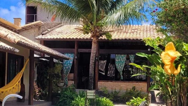 Una piscina con solárium alicatado, una palmera y un edificio con tejado de tejas.