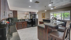 A kitchen with dark wooden cabinets, a stainless steel refrigerator, and a granite countertop.