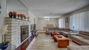 A spacious living room with a fireplace, a large sofa set, and a dining area.