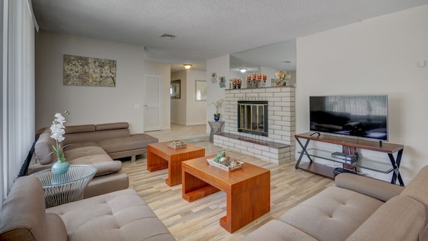 A modern living room with a sofa set, wooden coffee tables, a TV, and a fireplace.