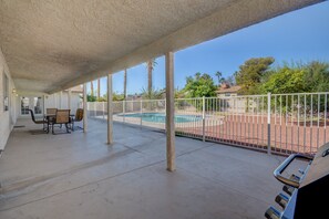 A covered patio area with a pool, outdoor seating, and a view of the surrounding landscape.