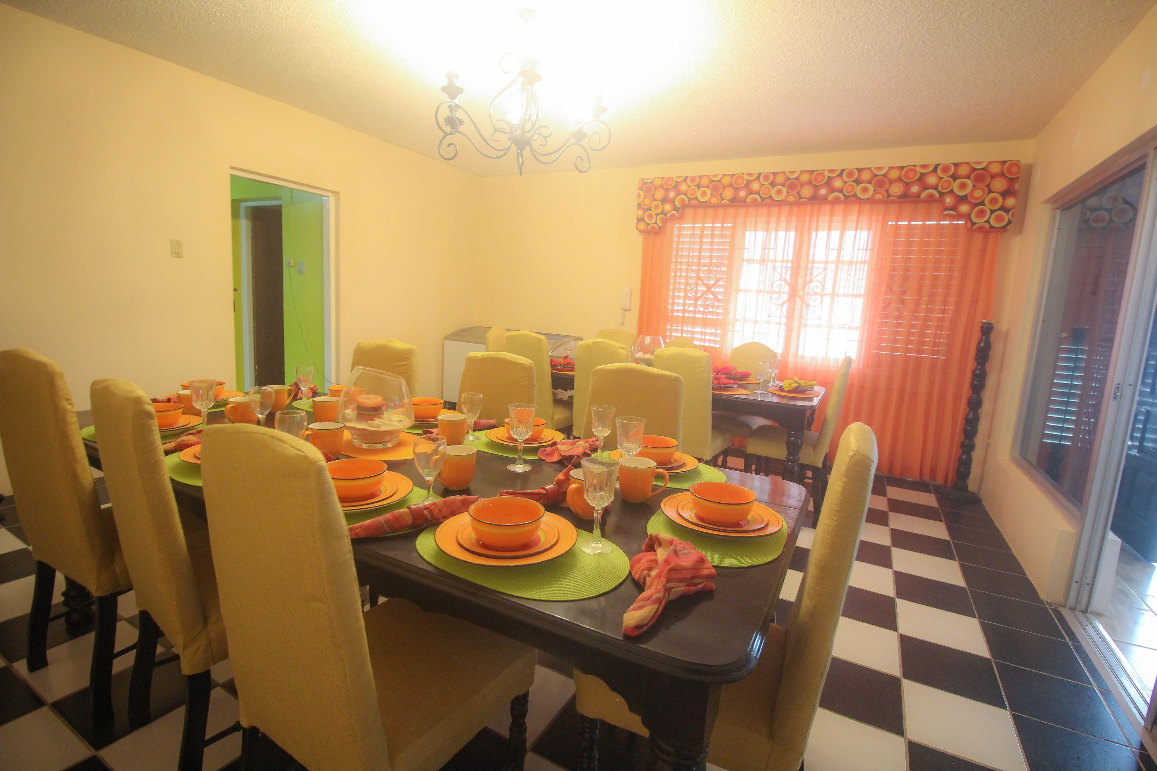 A dining area with a checkered floor, yellow chairs, and orange table settings.