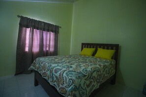 Un dormitorio con cama, cortinas y almohada amarilla.