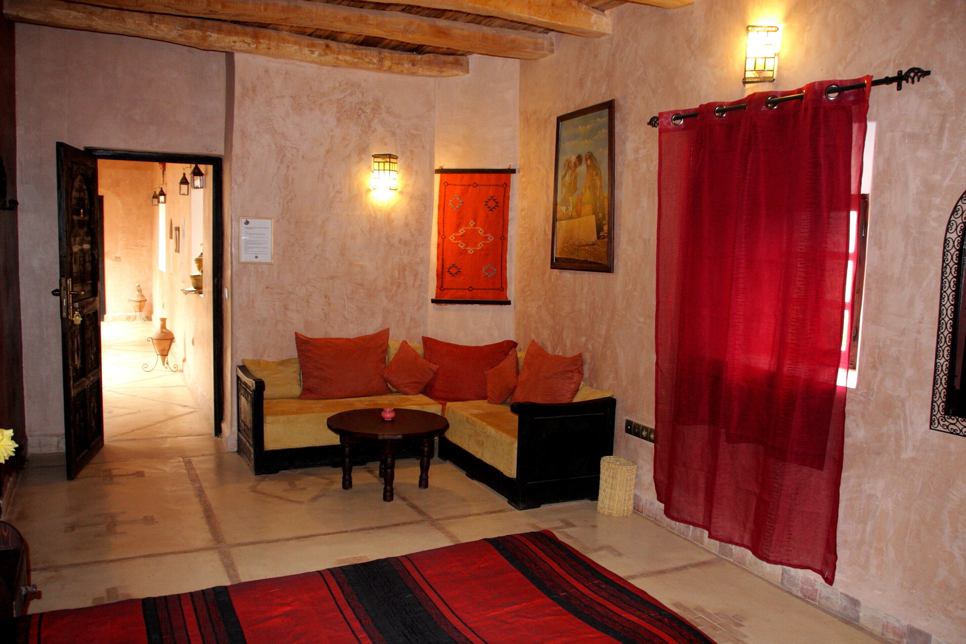 A living room with a sofa, a coffee table, and a red curtain.