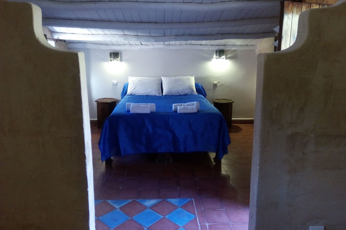 A room with a bed, two nightstands, and a tiled floor.