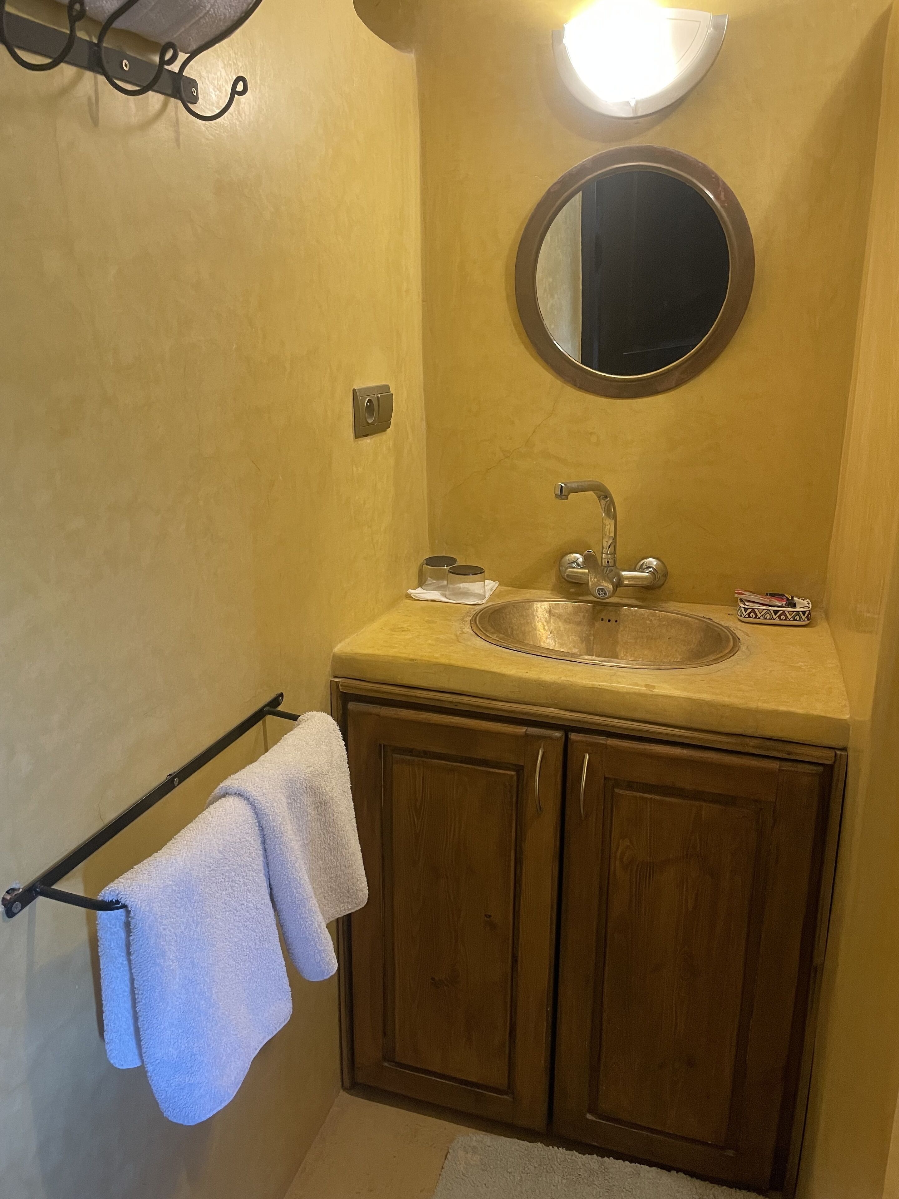 A bathroom with a sink, mirror, towel rack, and wooden cabinets.