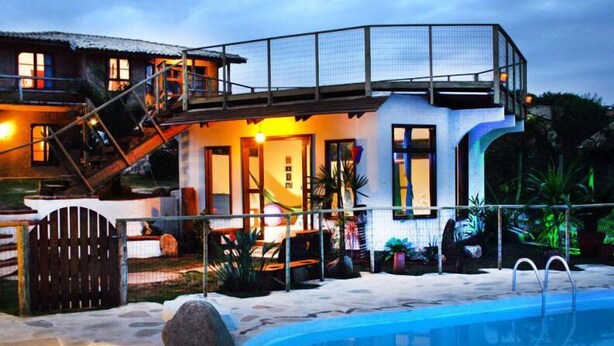 A modern house with a swimming pool, a covered patio, and a staircase leading to a second floor. - Pousada Gopak (Imbituba)