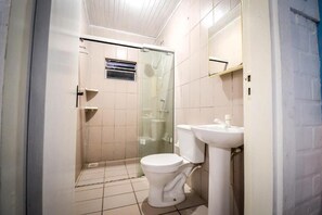 A bathroom with a toilet, sink, and glass shower enclosure. - Pousada Natureza (Florianópolis)