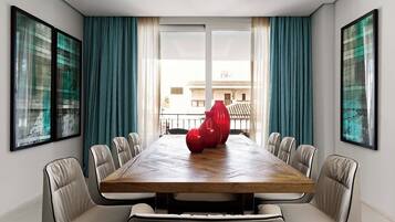 Un comedor moderno con una gran mesa de madera, sillas blancas tapizadas y jarrones rojos.