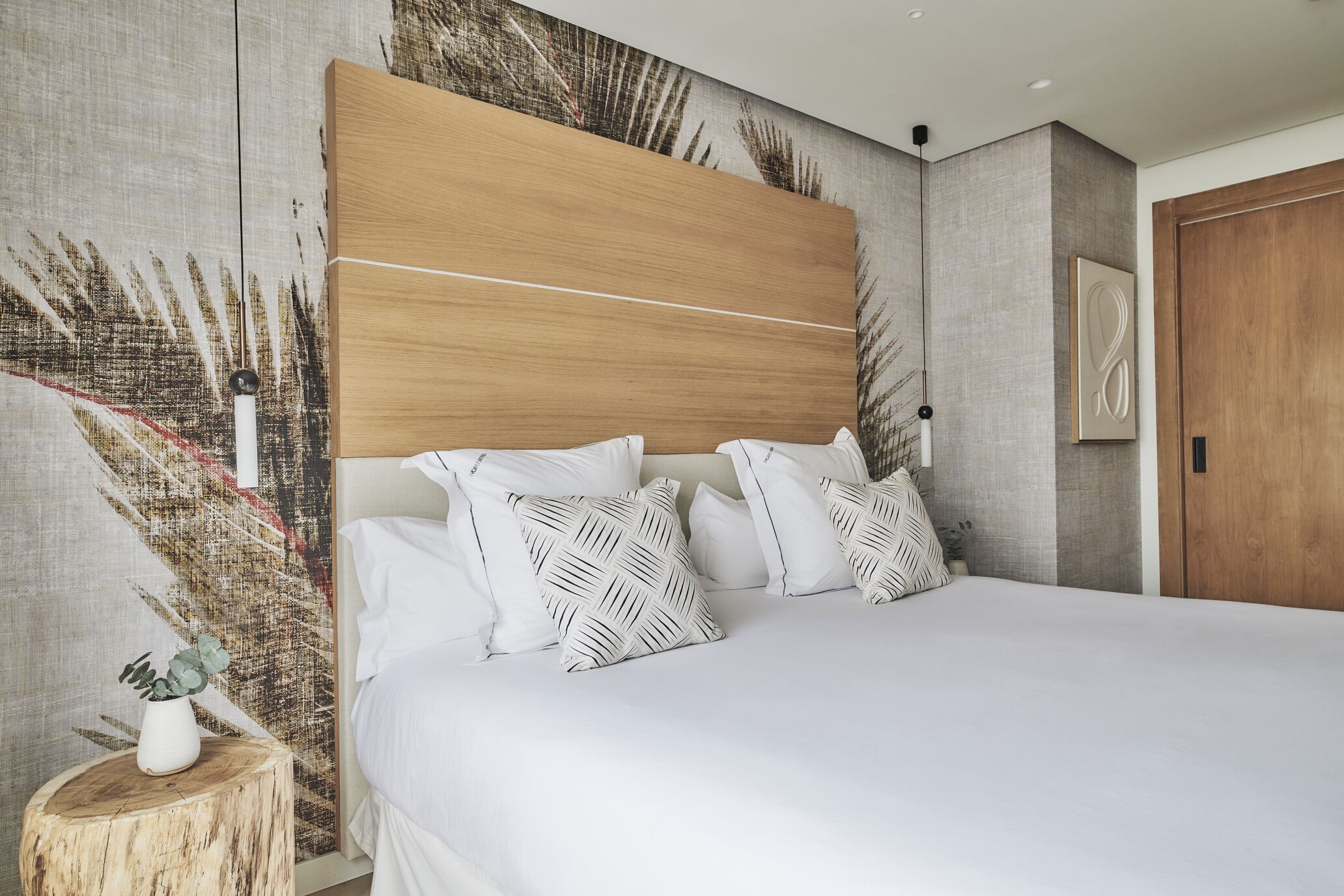 Un dormitorio moderno con una cama grande, cabecera de madera y un panel decorativo en la pared.