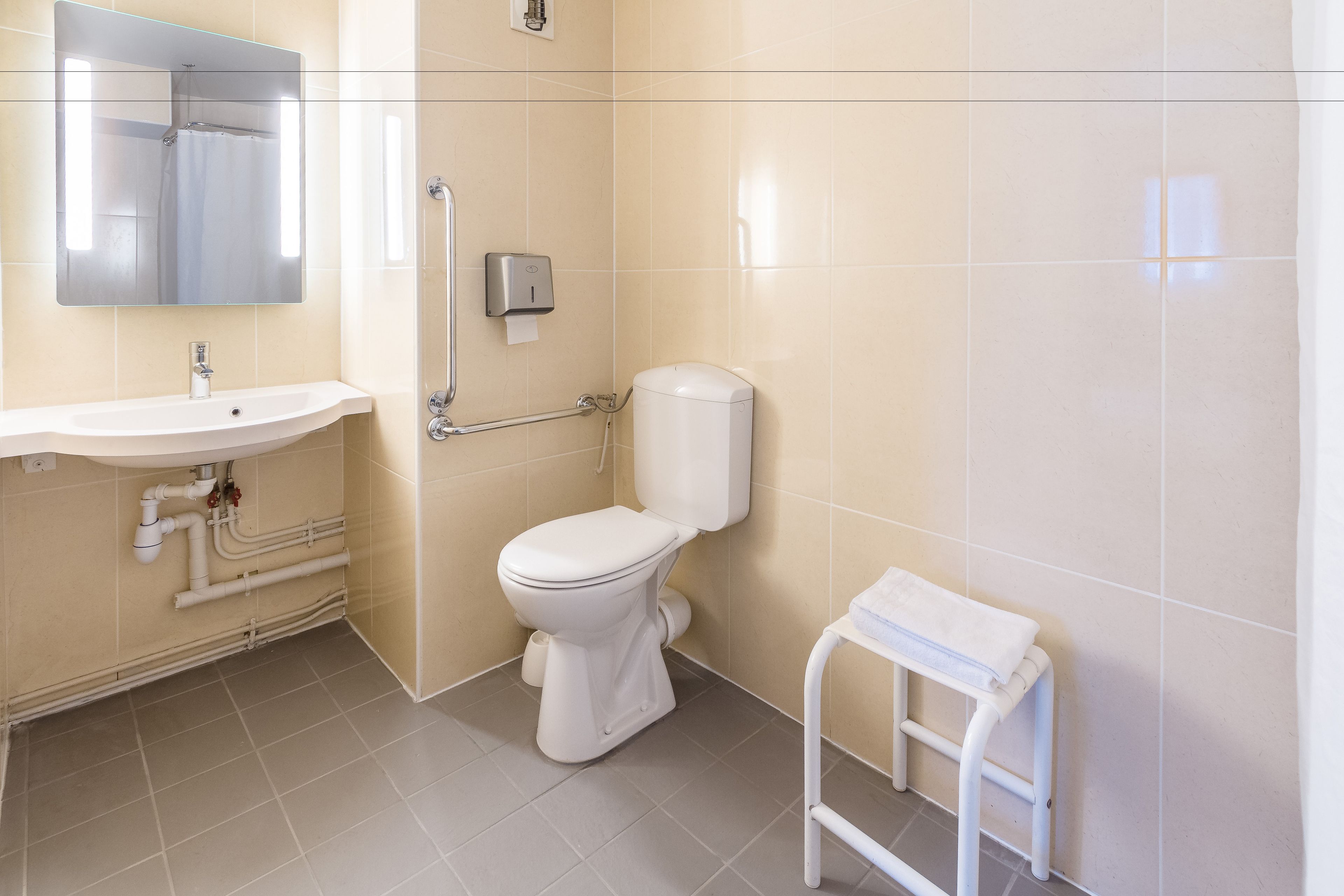 Een badkamer met een wastafel, toilet en een klein wit krukje.