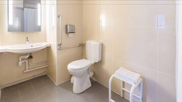 Een badkamer met een wastafel, toilet en een klein wit krukje.