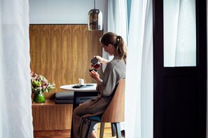 A person seated at a table with a cup and saucer, a vase with flowers, and a hanging light fixture. - West Hotel Sydney, Curio Collection by Hilton (Sydney)