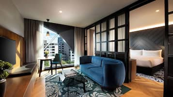 Una habitación de hotel moderna con sofá, una mesita de noche con un jarrón, cama y vistas a la ciudad.
